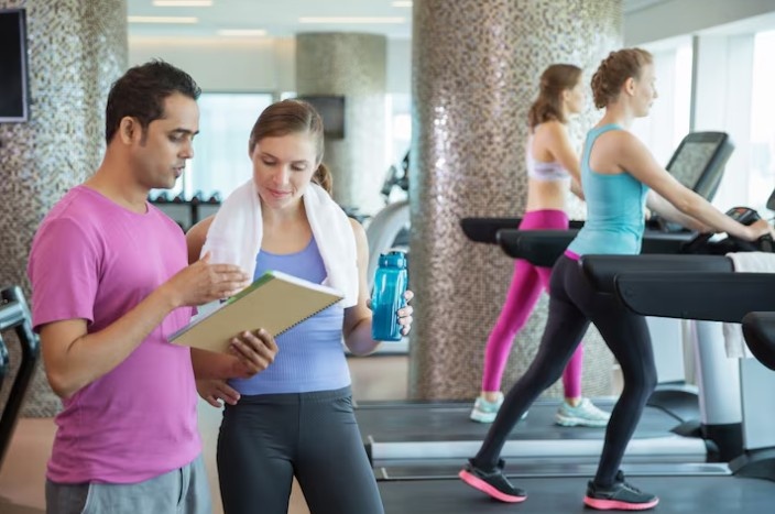 Fitness trainer guiding a woman during weight loss training at a gym in Bangalore